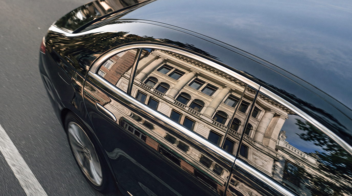 City facade reflected in the side of a chauffeured car