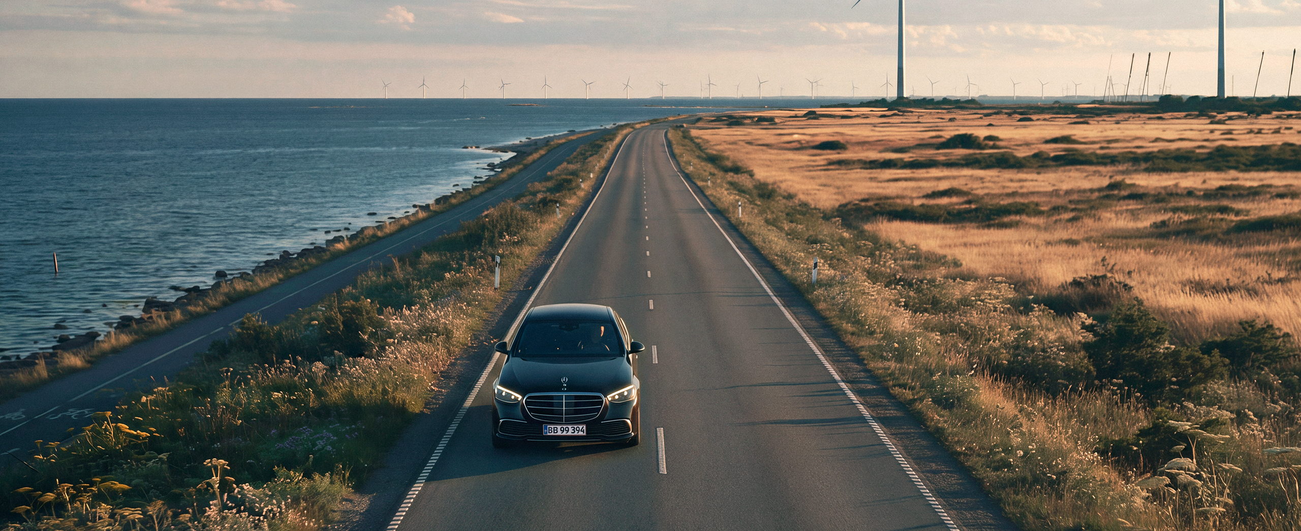 Chauffeured car on a coastal road at sunset